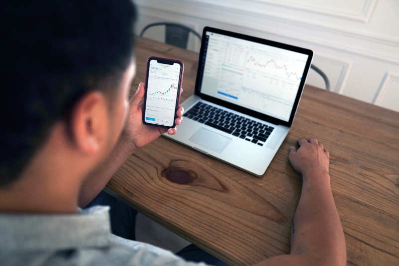 Trader at his notebook and smartphone trading online.